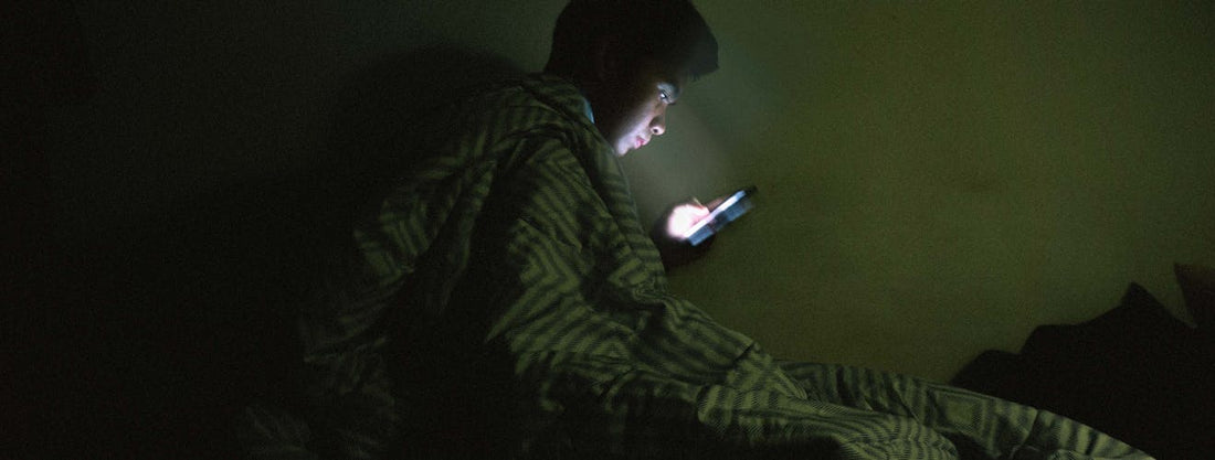 man on phone in bed searching for best sleep fan